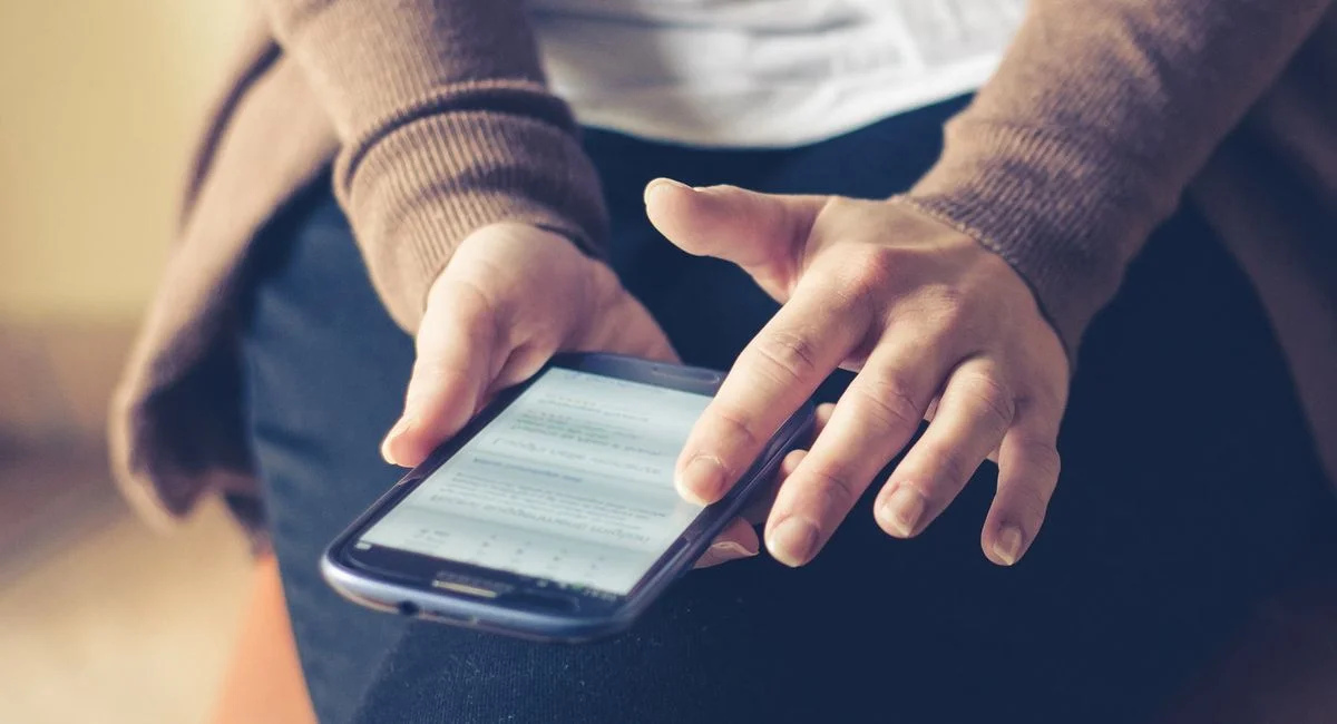 Close-up of adult using smartphone indoors, browsing web with focus on screen.